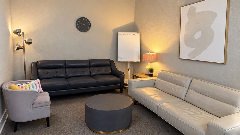 Frisco counseling room with two leather sofas, an armchair, a round coffee table and a whiteboard