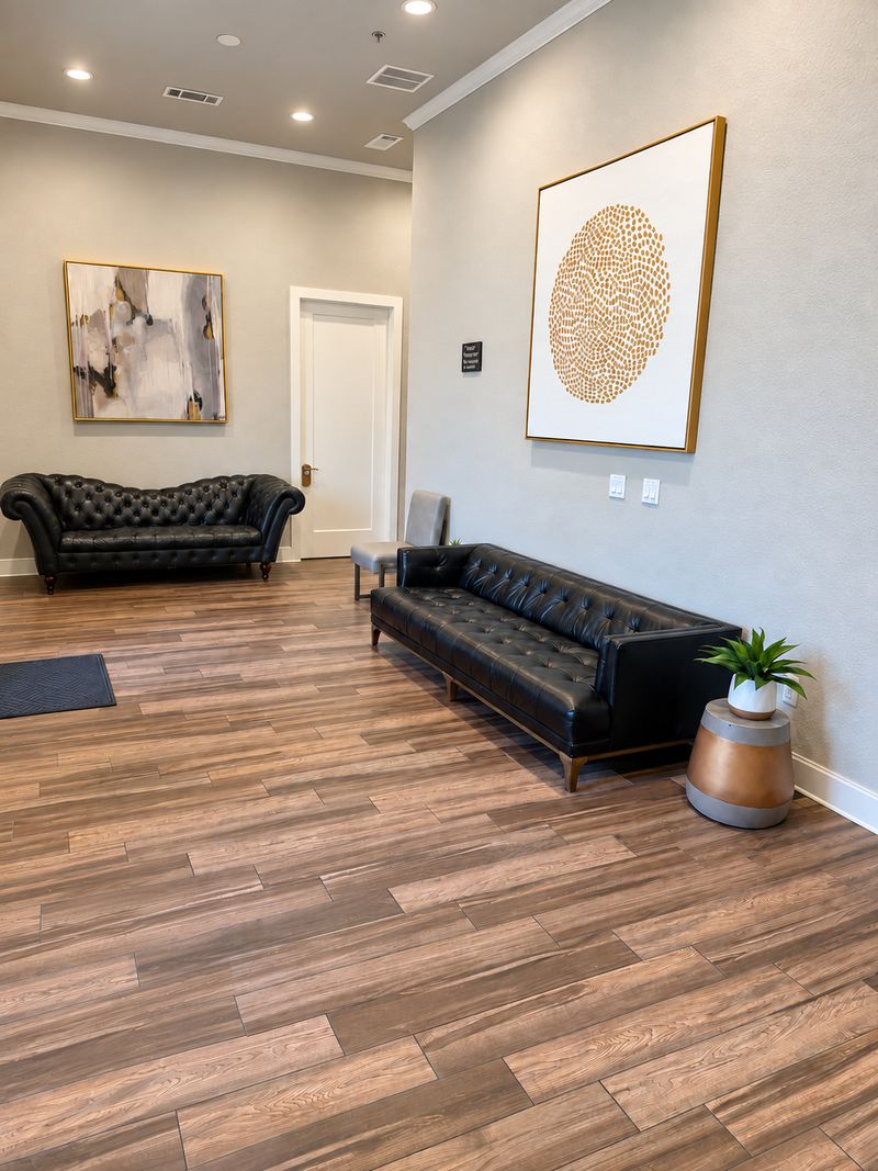 Waiting area at the Frisco office with leather sofas, wood floors and framed artwork